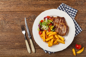 Grilled pork neck served with French fries and salad.