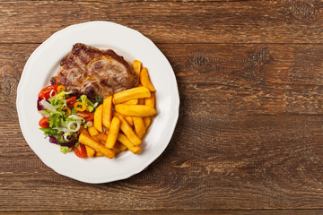 Grilled pork neck served with French fries and salad.