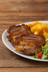 Grilled pork neck served with French fries and salad.