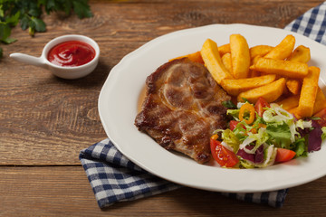 Grilled pork neck served with French fries and salad.