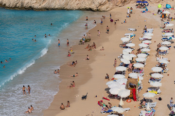 People enjoying sun and sea at the turquoise sea and sandy beach of Kaputas, Kas, Antalya, Turkey.