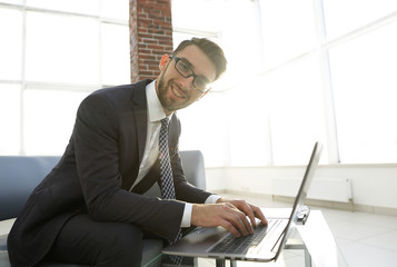 Young businessman using laptop and smiling