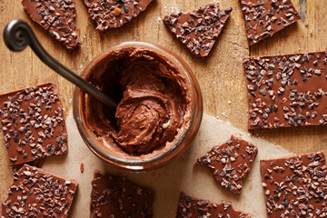 Top view of homemade chocolate paste with chocolate pieces on the wooden table.