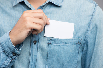 Young man who takes out blank business card from the pocket of his shirt