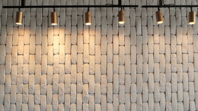 The white brick wall is hilighted with lanterns from above. Texture for background. Empty cement plane. Soft light from lamps is reflected from the wall. Retro loft space in a hipster style.