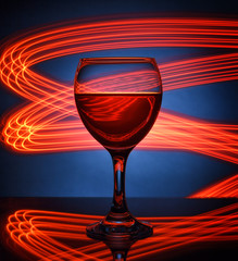 A glass of red wine closeup on the background of bright lights..