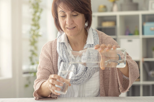 Woman Pouring Water From Bottle To Glass