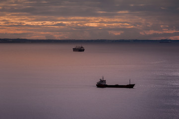 Seascape with ships and cloudy sky at sunset.