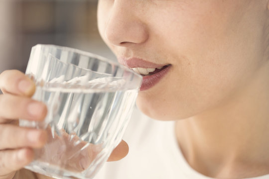 Young woman drinking glass of water close up