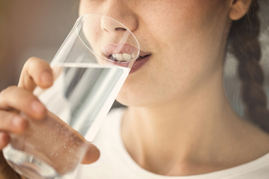 Young woman drinking glass of water close up view