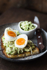 Mashed avocado, egg and cheese on toasted bread. Healthy lifestyle, healthy eating concept. Dark food photo, selective focus