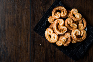 Palmier Cookies in Black Plate on Wooden Surface.