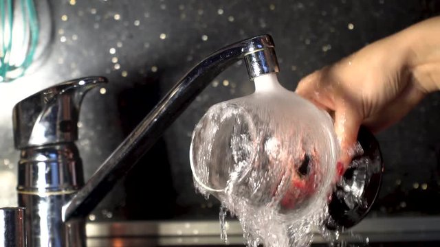 woman washing wine glass under tap water.Slow motion