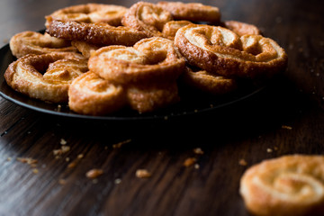 Palmier Cookies in Black Plate on Wooden Surface.