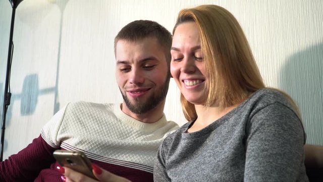 guy and girl look at smartphone and laugh