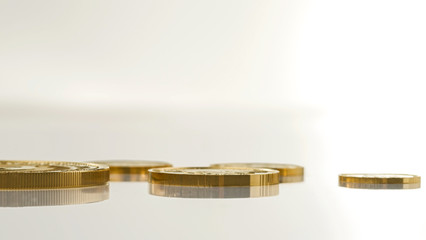 Gold coins of different sizes lie on a light surface. Selective focus.