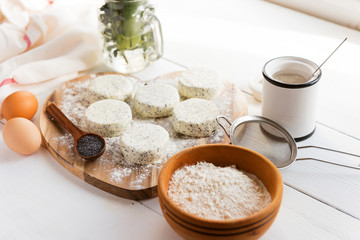 raw cheese cakes with poppy seeds on a wooden surface. with ingredients