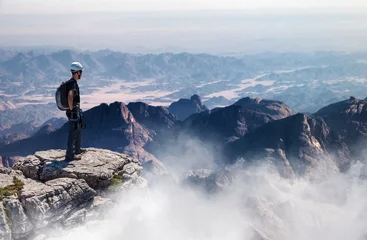 Fotobehang Mountain climber standing on summit with vast view © XtravaganT