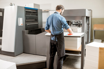 Printing operator working with offset machine at the printing manufacturing