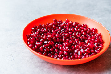 Organic Fresh Pomegranate Seeds in Red Bowl with Blue Background.