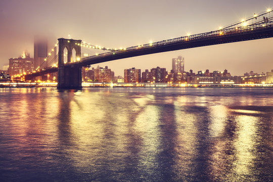 Brooklyn Bridge and the Manhattan on a foggy night, color toned picture, New York City, USA..