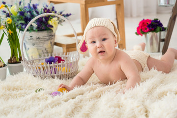 little boy in rabbit costume lays in flowers and easter rabbit