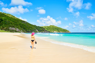 A woman tourist on tropical Beach Police Bay (white sand and turquoise sea) , south of Mahe, Seychelles