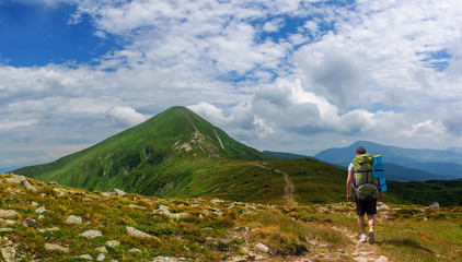 A tourist with a large backpack rises to Goverla mountain in Carpathian mountains Ukraine