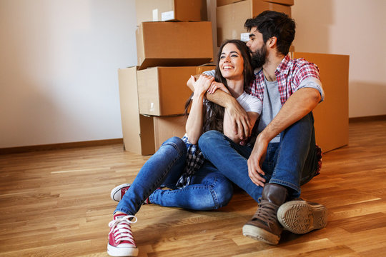 Young couple moving into a  new home.Sitting on floor in empty apartment .Real estate concept.