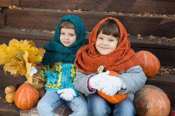 two adorable little girls holds pumpkin autumn day outdoors.