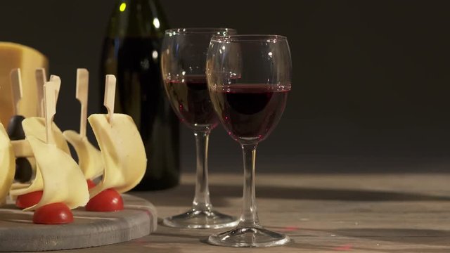 Cheese and wine tasting. Different types of cheese wedges, cheese skewered appetizers, and glasses with red wine on wooden table. Dolly shot