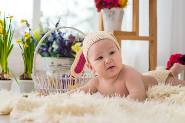 little boy in rabbit costume lays in flowers and easter rabbit