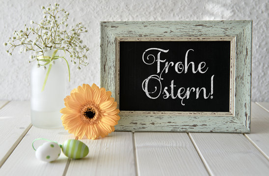 Spring flowers, Easter decorations and a blackboard on white table, text
