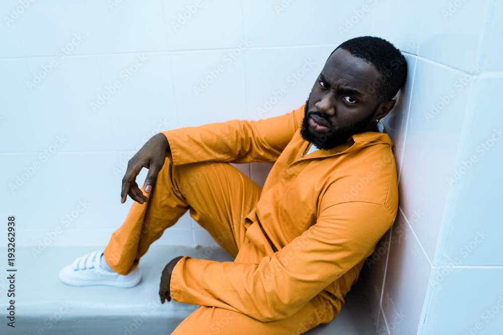 Wall mural african american prisoner sitting on bench and looking at camera