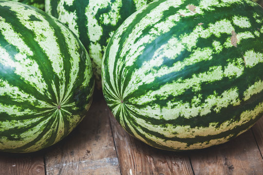 group of striped watermelons lies on wooden boards