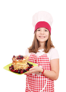 Happy little girl cook with sweet pancakes on plate
