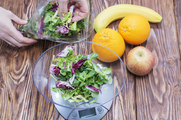 green lettuce leaves on the kitchen scale. banana Apple orange on wooden table
