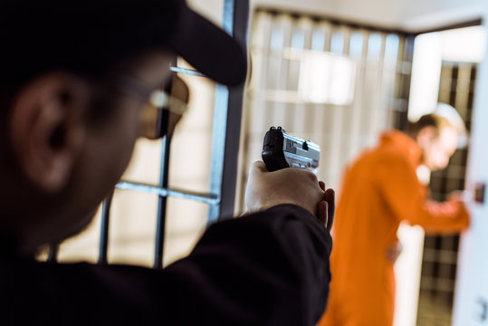 prison officer aiming gun at escaping prisoner