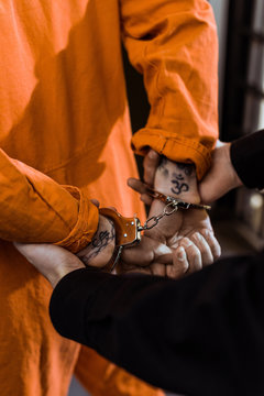 cropped image of prison officer holding convict in handcuffs