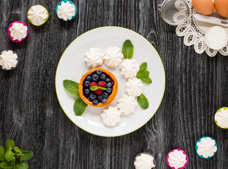 Sweet white meringue and other components on a wooden background, free space for text.