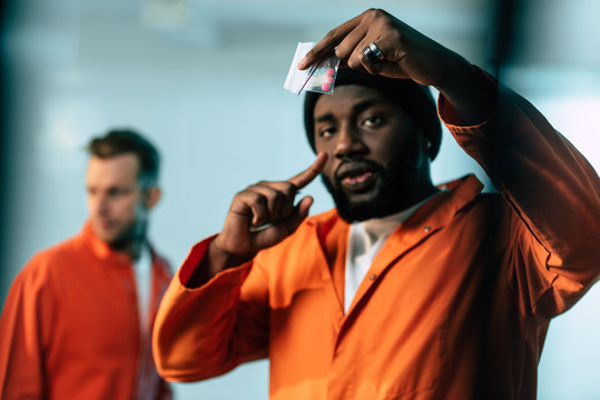 african american prisoner pointing on drugs at prison cell