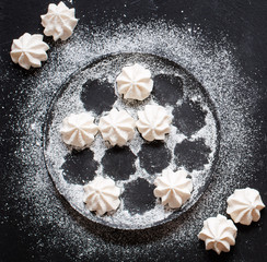 Sweet white meringue on a black wooden background, free space for text.