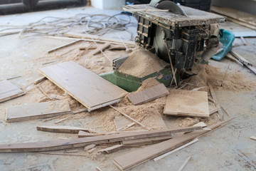 Electric saw for cutting parquet boards during the renovation of an apartment. Sawdust and advanced pieces of parquet boards under the oak wood cutting machine