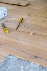 Oak colored parquet during installation on an old stoneware floor near an open window. Grazing light in the morning during the renovation of an apartment