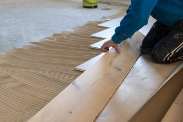 Renovation of an apartment, skilled worker uses a plastic hammer when installing pre-finished...