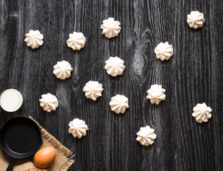 Sweet white meringue and other components on a wooden background, free space for text.