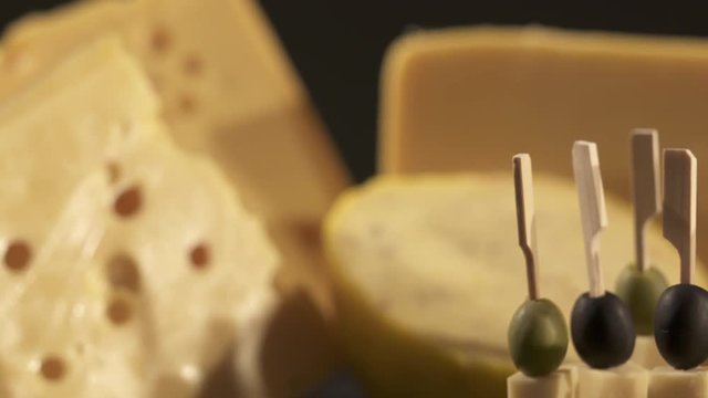 Cheese and wine tasting. Different types of cheese wedges, cheese skewered appetizers, and glasses with red wine on wooden table. Dolly shot