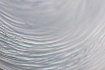 circular wave motion in a fluid system. blue gray background for a liquid pushed into a circular...