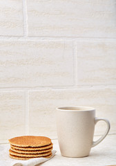 Close-up white cup of coffee with waffles on white background, top view