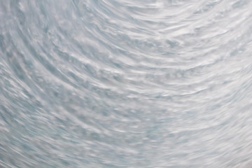 Fototapeta premium circular wave motion in a fluid system. blue gray background for a liquid pushed into a circular motion. waves and concentric circles with ripples as abstract and generic background. simulation of flu